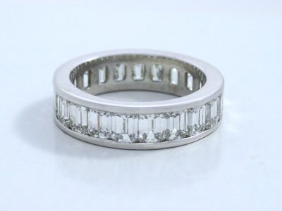 Diamond eternity band with twenty-one emerald cut diamonds with 5.31 total carat weight channel-set in a platinum band 