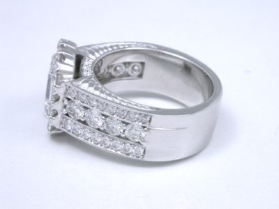 Diamond  ring with 1.20-carat emerald cut diamond prong-set in an 18-karat white-gold mounting with 8 shared-prong set on the shank and 38 pave-set diamonds in flanking rows on the shank and 3 on each side of the shank under the head