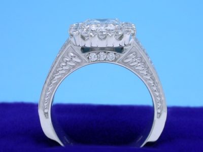 1.20-carat emerald cut diamond prong-set in an 18-karat white-gold custom mounting with hand-carved designs on the side of the shank