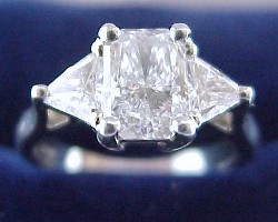 1.03 carat Radiant Cut diamond graded E color, VS2 clarity, with 1.40 ratio set in a platinum mounting with 0.75 tcw of trillion cut side diamonds