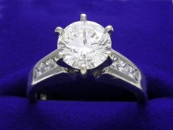 1.70 carat Round Brilliant diamond graded H color SI2 clarity and prong-set in mounting with six Princess cut Diamonds